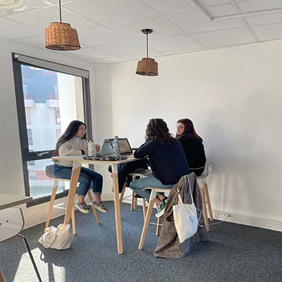 3 étudiantes autour d'une table avec ordinateurs, en train d'échanger sur un projet